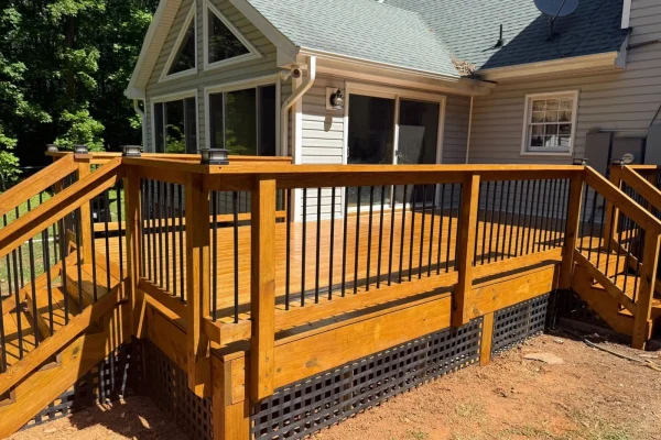 Wraparound wood deck with black balusters beside a gabled screened porch, Durham NC