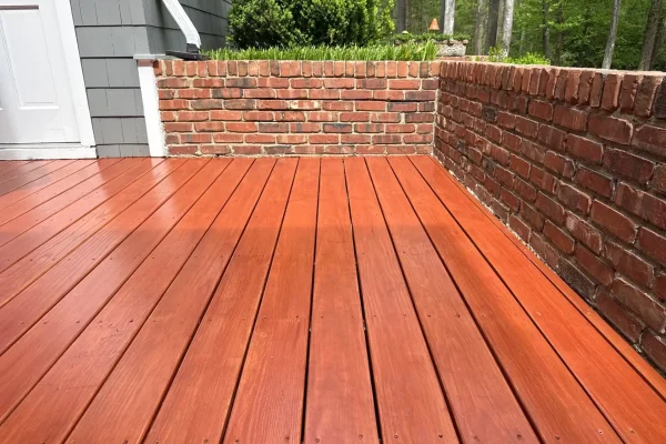 Freshly stained cedar-tone wood deck boards against a brick garden wall, Cary NC